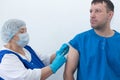 elderly nurse gives injection to man vaccination