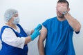 elderly nurse gives injection to man vaccination