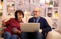 Elderly old couple using modern laptop to chat with their grandson