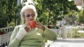 Elderly old woman with injured hand drinking coffee outdoor Royalty Free Stock Photo