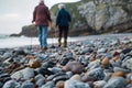 elderly pair with walking sticks exploring a rocky beach