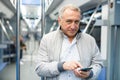 Elderly passenger is engrossed in information on smartphone while traveling in subway car