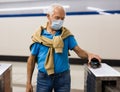 Elderly passenger in protective mask pays for a metro ride using mobile phone