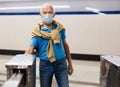 An elderly passenger in a protective mask pays for a subway ride