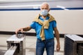 elderly passenger in a protective mask pays for a subway ride using a mobile phone