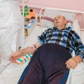 An elderly patient lies under a dropper