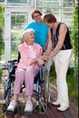 Elderly Patient on Wheel Chair with Two Caregivers.
