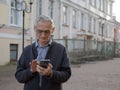 Elderly person is holding a mobile phone in his hands. Senior man is texting on smartphone. Old man is using cellphone Royalty Free Stock Photo