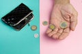 An elderly person holds the coins over the old empty wallet. The concept of poverty in retirement Royalty Free Stock Photo