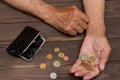 An elderly person holds the coins over the old empty wallet. Royalty Free Stock Photo