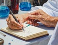 Elderly Person Writing in Notebook with Assistance Royalty Free Stock Photo