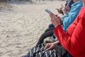 Elderly persons sitting on a bench at the seaside and use smartphones