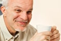 Elderly ponders humor, coffee or tea in hand