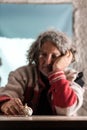 Elderly poor man with dirty hands sitting holding a garlic bulb