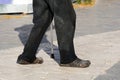 An elderly poor man walks with a cane down