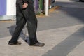 An elderly poor man walks with a cane down