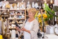 Elderly positive retired woman chooses an Indian figurine at hardware store