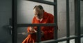 Elderly prisoner eats food sitting in prison cell in jail Royalty Free Stock Photo