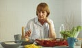 Elderly retired grandmother stay at home with unhappy face sitting alone on eating table in house. Depressed mature Senior old Royalty Free Stock Photo