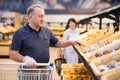 elderly retired man buying bread and pastries in grocery section of the supermarket Royalty Free Stock Photo