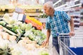 Elderly retired man buying turnip in grocery department of supermarket