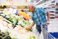 Elderly retired man buying turnip in grocery department of supermarket