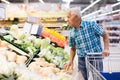 Old age man choosing turnipes in supermarket