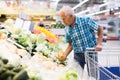 Old age man choosing turnipes in supermarket