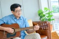 An elderly retired man spends his holidays at home playing the guitar for fun. Royalty Free Stock Photo