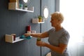 Elderly retires woman wiping dust from shelf