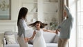 Grandmother adult daughter and granddaughter dancing in modern living room