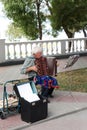 An elderly sad male musician plays for passers-by on the seafront