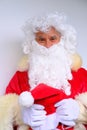 Elderly santa claus in a suit, with a white beard congratulates children and adults, shows with his hands, the concept of