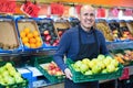 Elderly seller offering seasonal ripe fruits in local grocery