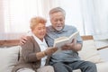 Elderly senior asian couple sitting on sofa reading book together at home.Retirement grandmother and grandfather spend time Royalty Free Stock Photo