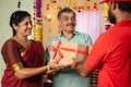 Elderly senior couple receiving ordered online delivery box from delivery person - concept of diwali festive gifting