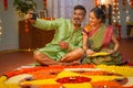 elderly senior couple taking selfie during diwali festive preparation at home in front of flower rangoli - concept of