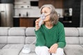 An elderly senior female is using inhaler