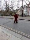 Elderly senior lady crossing a road with a walking stick