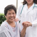 Elderly senior patient Asian old aging person in nursing hospice home holding geriatrician doctor`s hand having happy health Royalty Free Stock Photo