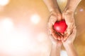 Elderly senior person or grandparent's hands with red heart in support of nursing family caregiver