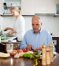 Elderly senior preparing vegetarian food and mature wife doing