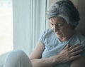 Elderly senior sick disabled, sad woman in pain and suffering sitting by the window in the hospital. Royalty Free Stock Photo