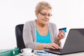 Elderly senior woman with credit card and laptop paying over internet for utility bills or online shopping Royalty Free Stock Photo