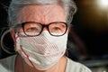 Elderly senior woman with glasses wearing hand made cotton mouth nose virus face mask. Coronavirus covid19 outbreak prevention Royalty Free Stock Photo