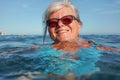 Elderly senior woman with gray hair, swimming in sea on sunny day, closeup to her smiling face Royalty Free Stock Photo