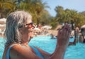 Elderly senior woman with grey hair, wearing blue swimsuit doing water aerobics in hotel pool, clapping her hands Royalty Free Stock Photo