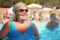 Elderly senior woman with grey hair, wearing blue swimsuit doing water aerobics in hotel pool Royalty Free Stock Photo