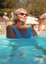 Elderly senior woman with grey hair, wearing blue swimsuit doing water aerobics in hotel pool Royalty Free Stock Photo
