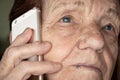 Elderly senior woman holding gold coloured phone next to her ear, closeup detail Royalty Free Stock Photo